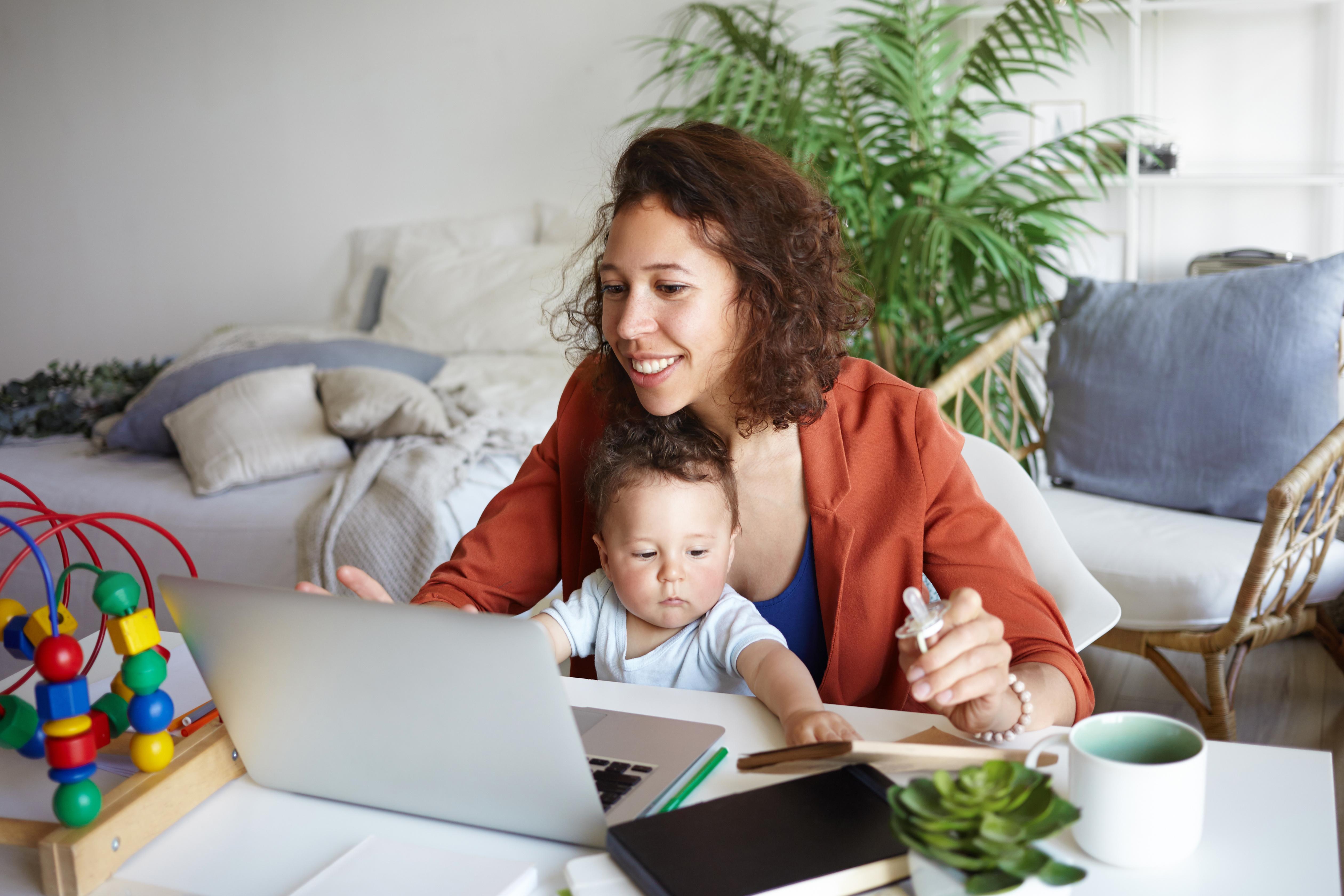 woman working on a laptop with a baby in her lap